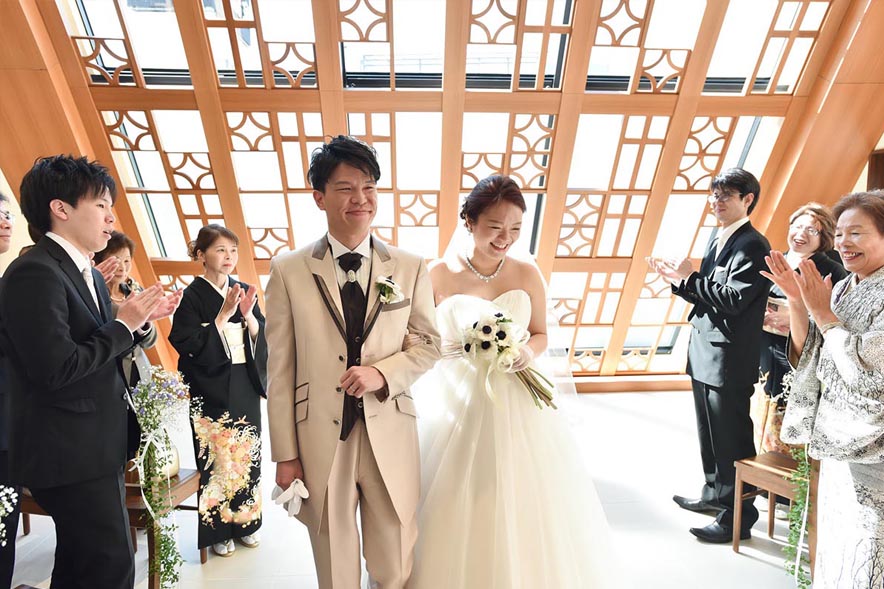 陽の射す明るいチャペルのバージンロードを歩く新郎新婦